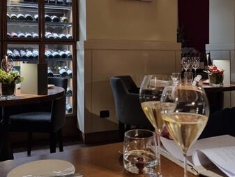 Interno di una sala di un ristorante, con tavolo in primo piano, mise en place, tovagliolo e calici