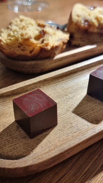 cioccolatino cubico su vassoio in legno e fetta di panettone sullo sfondo