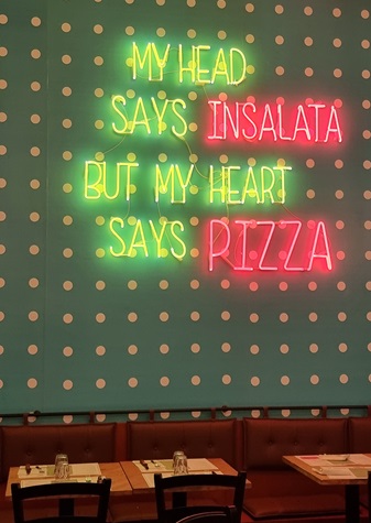 Neon anni '80 con scritta in inglese la mia testa dice insalata il mio cuore dice pizza, interior design Glory POP pizzeria a Milano