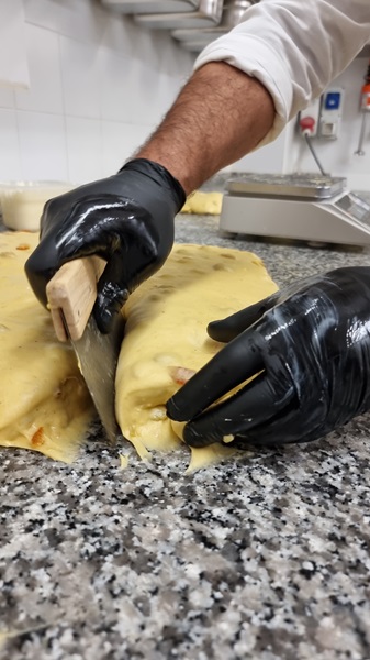 Chef che taglia impasto del panettone con un tarocco in acciaio
