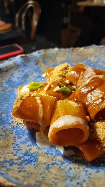 Piatto azzurro con paccheri al sugo di granchio e polvere di anacardi