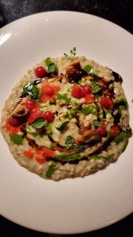 Piatto di risotto con salsa verde, ribes e fondo di carne su piatto bianco