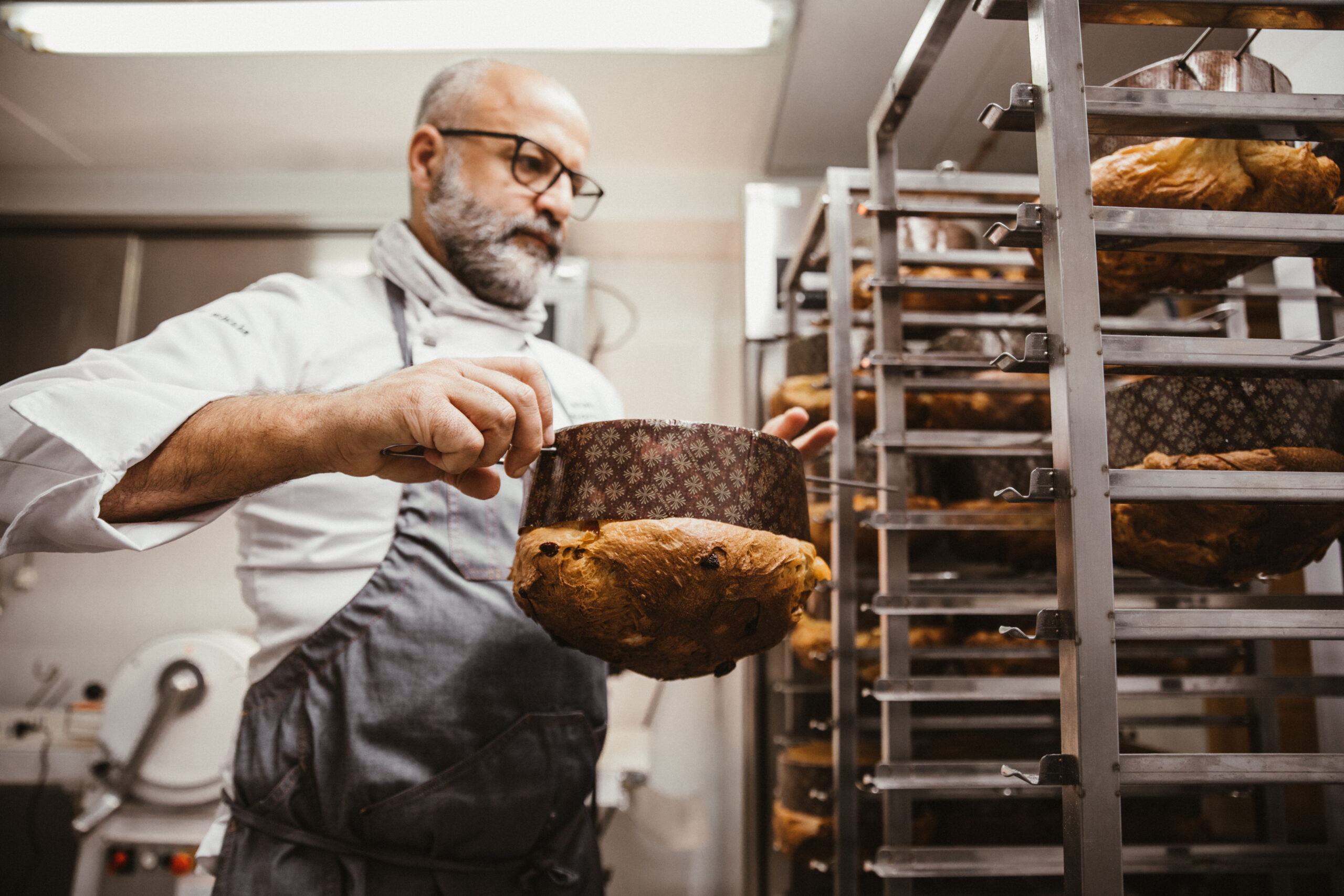 Matteo Sormani della Walser Schtuba capovolge un panettone cotto sulla rastrelliera per farlo raffreddare