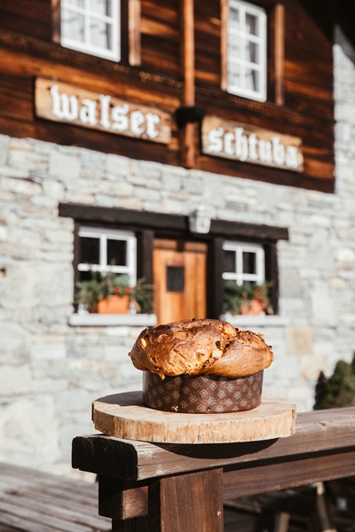 Panettone artigianale su un tronco di legno davanti all'ingresso di una locanda