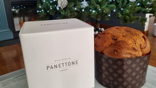Panettone intero con accanto la sua confezione in cartone bianco