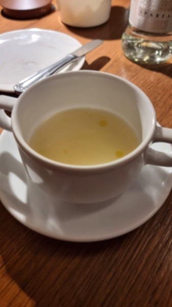 Tazza da consommé con brodo all'interno su tavolo in legno