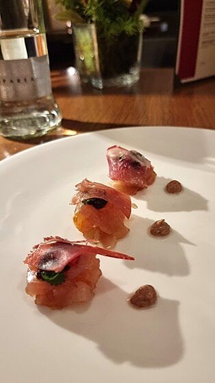 tartare di ricciola in piatto bianco su tavolo in legno
