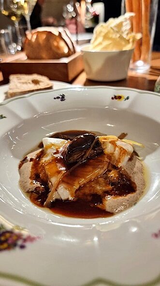 Piatto in ceraica con pietanza all'interno su tavolo in legno in un ristorante