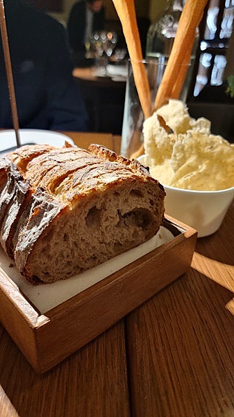 Pane, burro mantecato e grissini su un tavolo di legno in ristorante