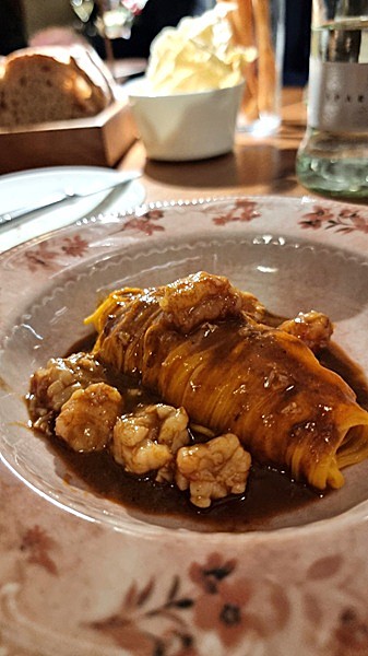 Tagliolini in un piatto di ceramica su tavolo in legno con crostacei e fondo di cottura