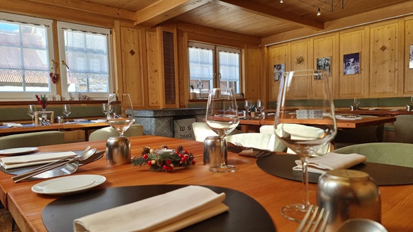 la sala interna del ristorante della locanda Walser Schtuba con tavoli in legno apparecchiati per cena con calici, posate e tovaglioli